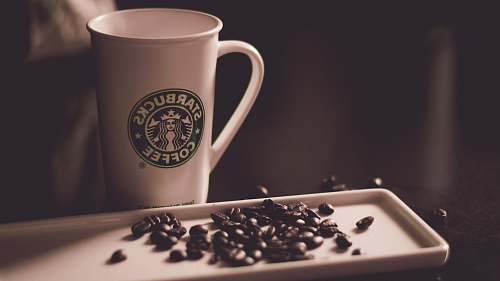 coffee cup coffee beans beside Starbucks coffee mug coffee beans